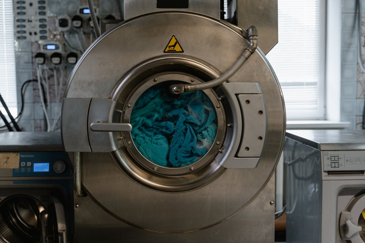 Large industrial washing machine with blue fabrics in a laundry facility.